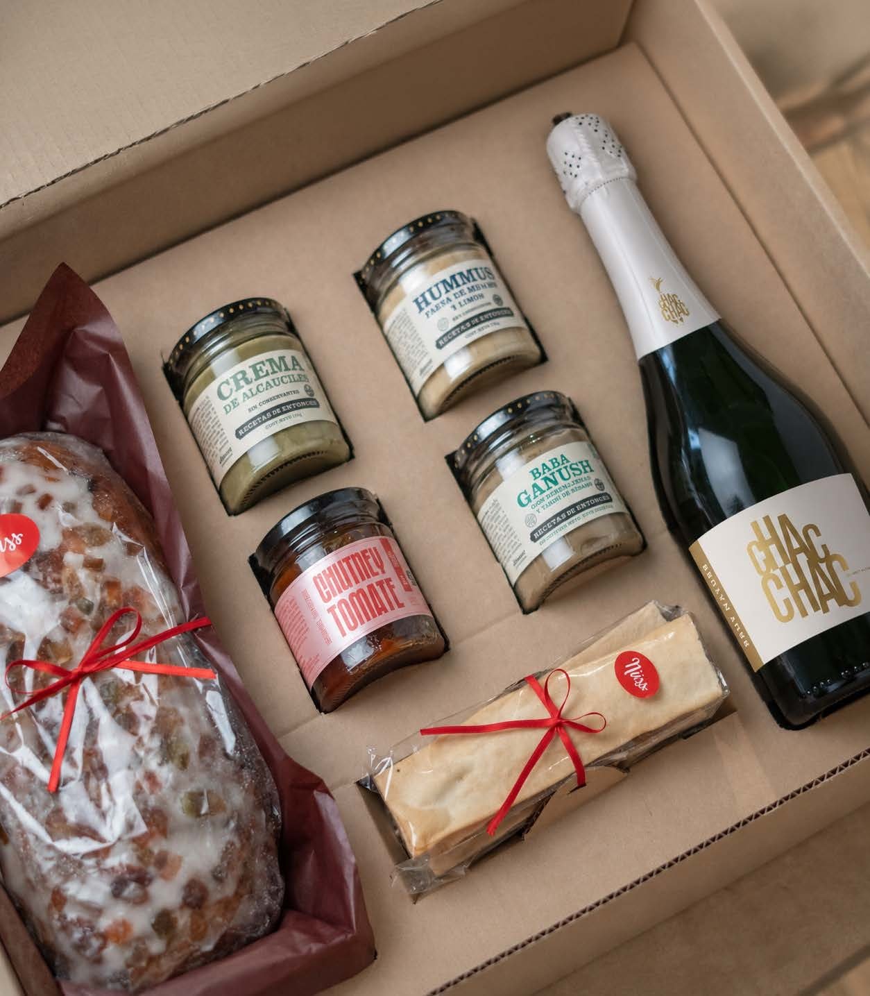 Caja abierta con panettone, cintas, las cuatro conservas y el Brut Nature